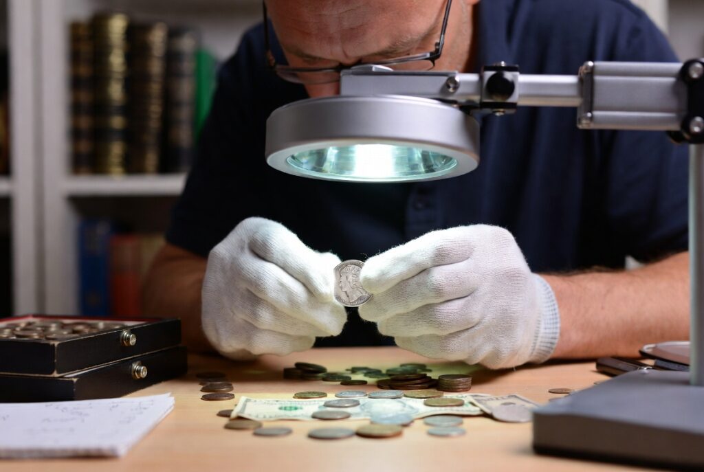 Expert numismatist examining inherited rare coins under magnification during professional appraisal.