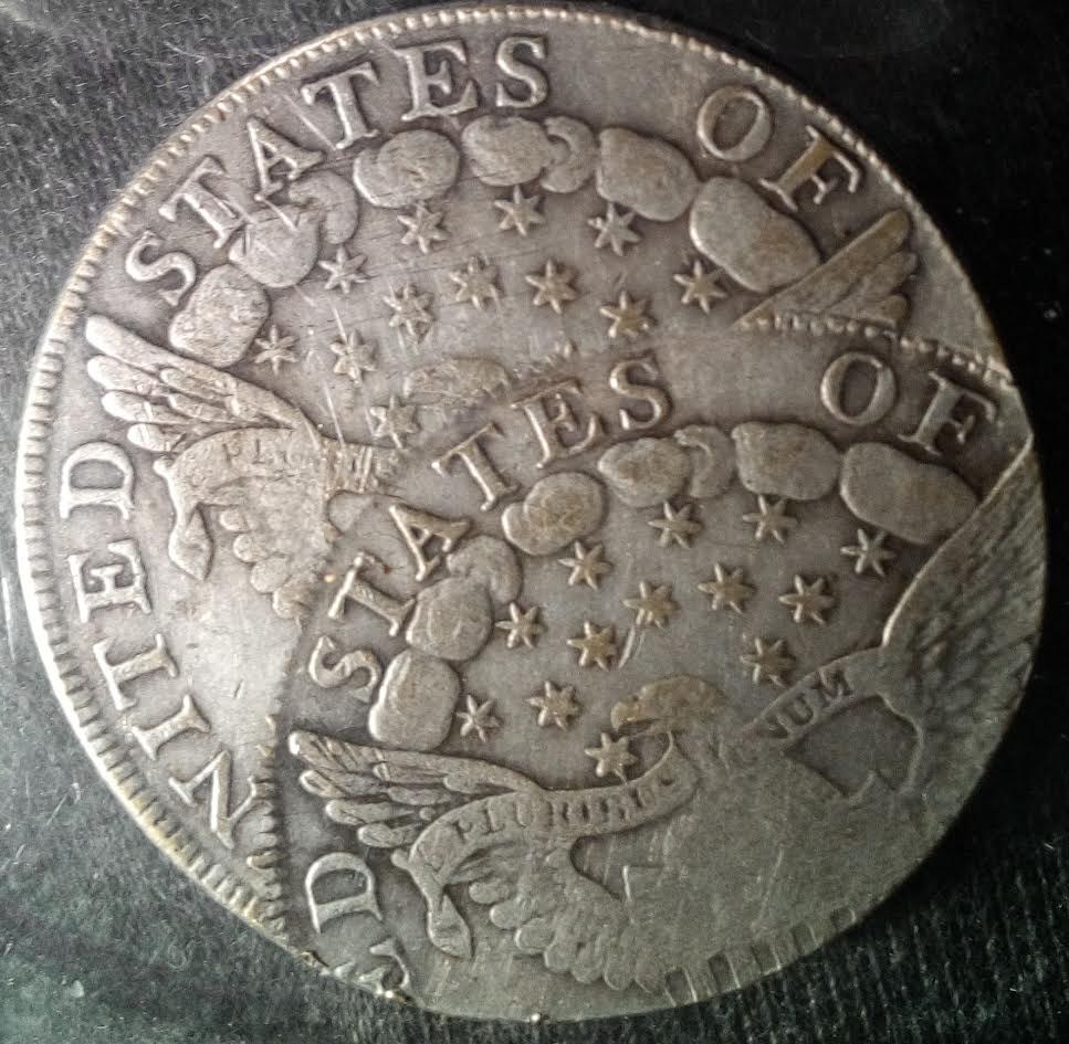 Reverse of a counterfeit double-struck Draped Bust half dollar showing two overlapping heraldic eagles, stars, clouds and "STATES OF" lettering on black velvet