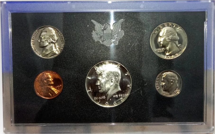 The clear lens of a 1969 U.S. Mint proof set holding a Kennedy half dollar, Washington quarter, Roosevelt dime, Jefferson nickel and Lincoln cent