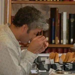 Photo of a coin appraiser examining a coin through a jeweler's loupe