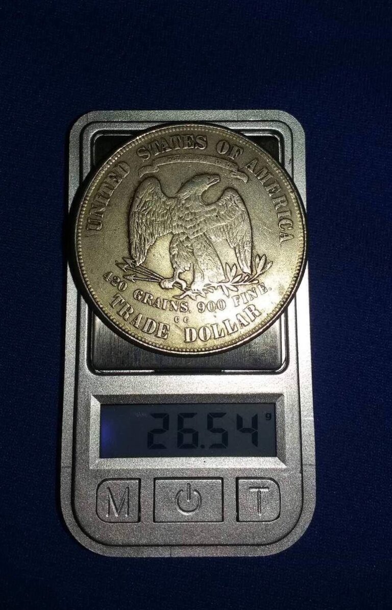 Counterfeit 1876 trade dollar, reverse, on a scale