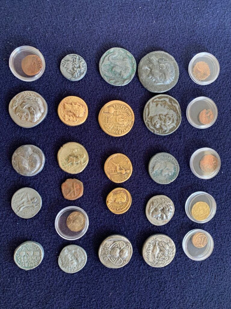Lot of about two dozen counterfeit ancient coins on a blue background