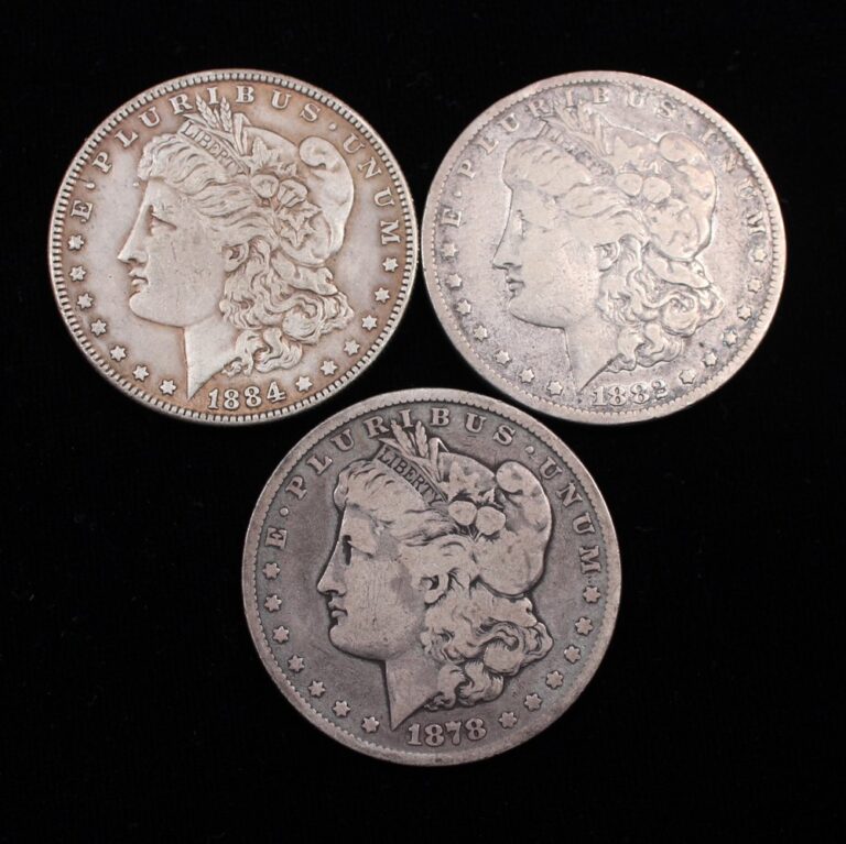 Three counterfeit Morgan silver dollars on a black background