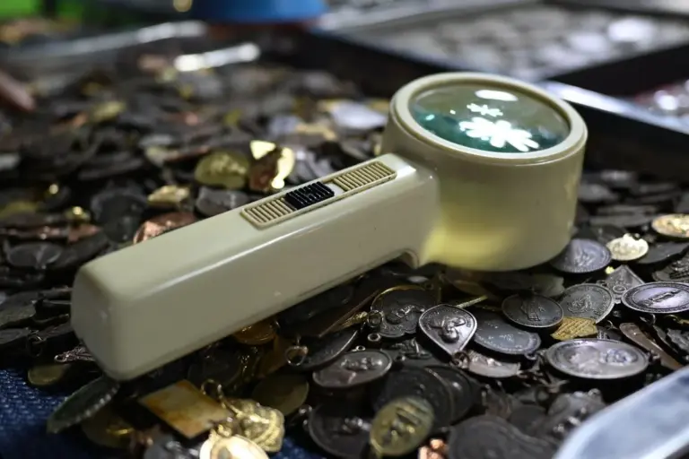 Lighted magnifying glass resting on a pile of old coins and medallions