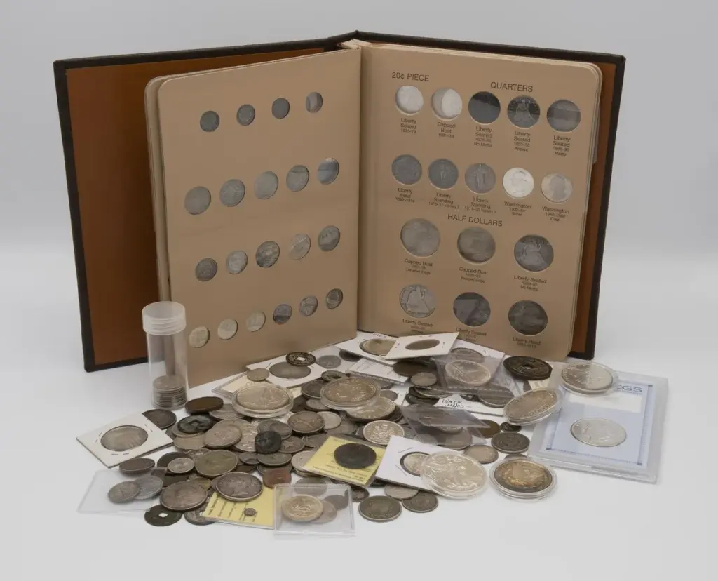 A real coin collection: an open album of U.S. twenty-cent pieces, quarters and half dollars, with loose U.S. and world coins, flips, a coin tube and a slabbed Morgan dollar in front