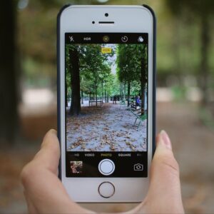 Photo of a hand holding a smartphone with the camera open, ready to send coin photos for a free appraisal