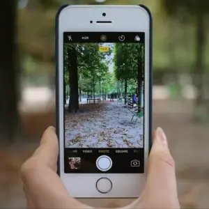Photo of a hand holding a smartphone with the camera open, ready to send coin photos for a free appraisal